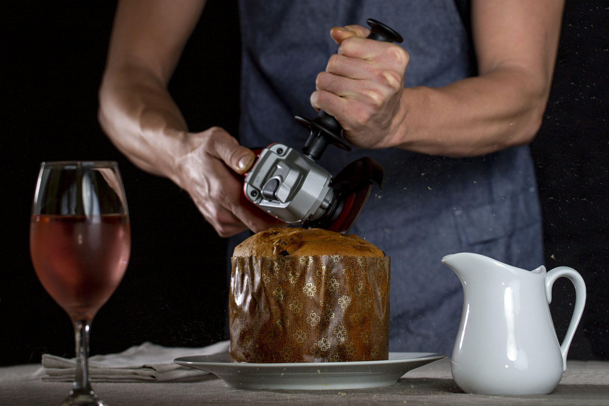 Hands holding an angle grinder that is being used to cut a fruit cake