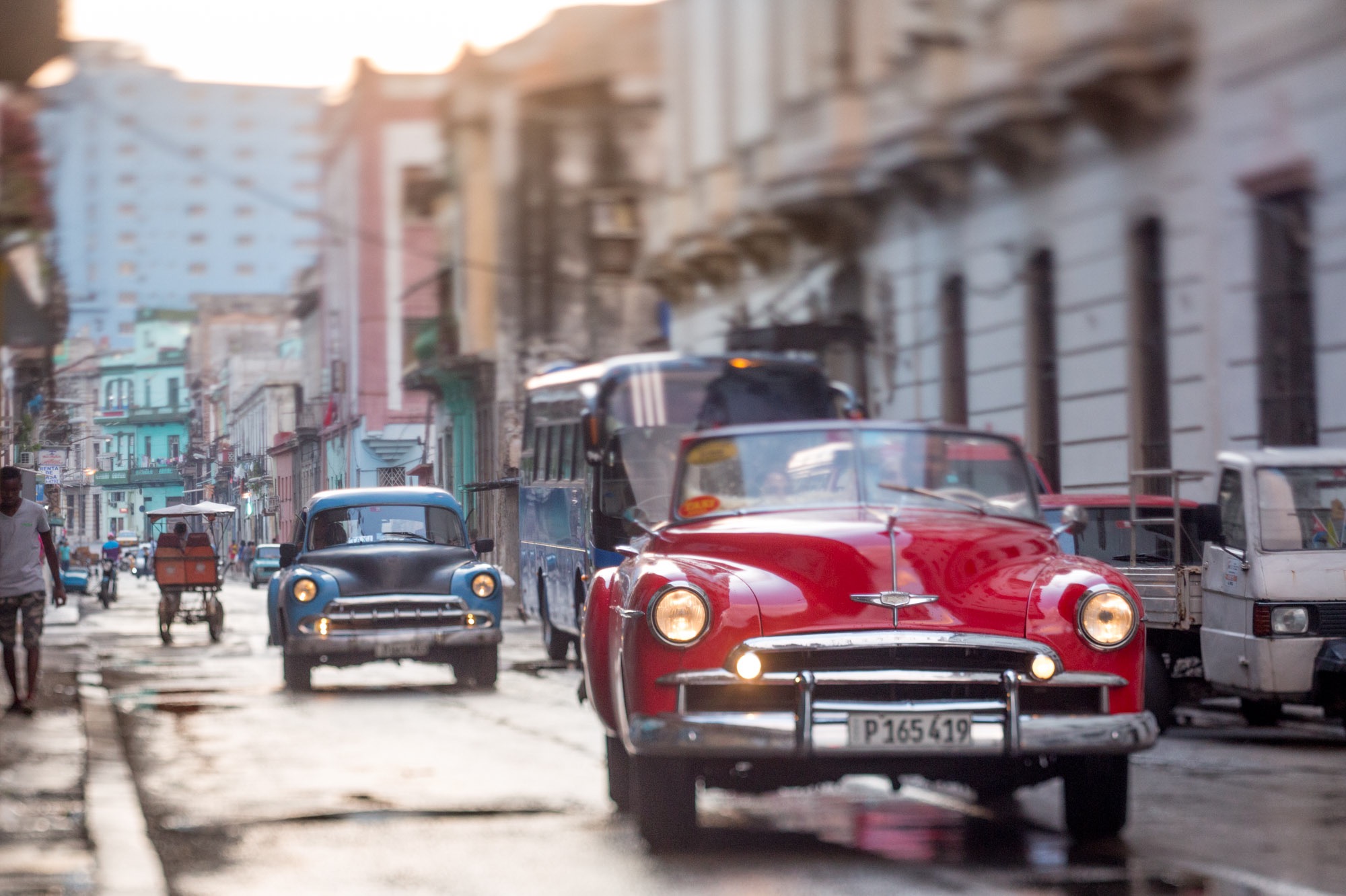 Classic cars driving on a wet street in Havana.