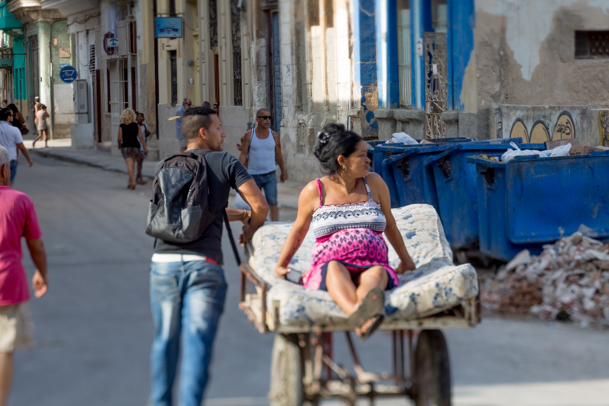 A man carrying a pregnant woman on a cart.