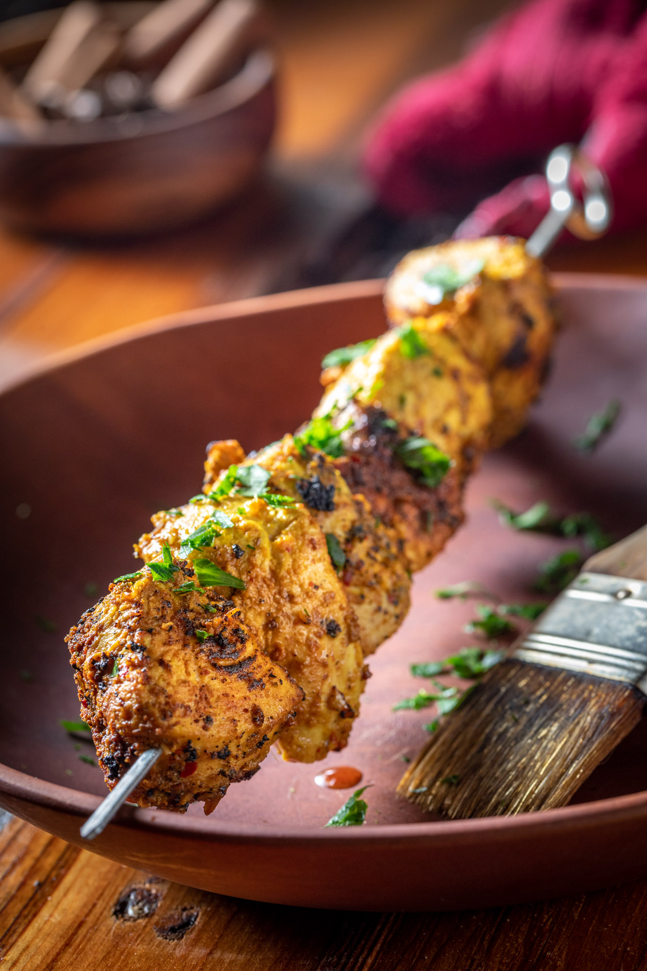 chicken tikka skewers getting dressed with cilantro and oil for food photography