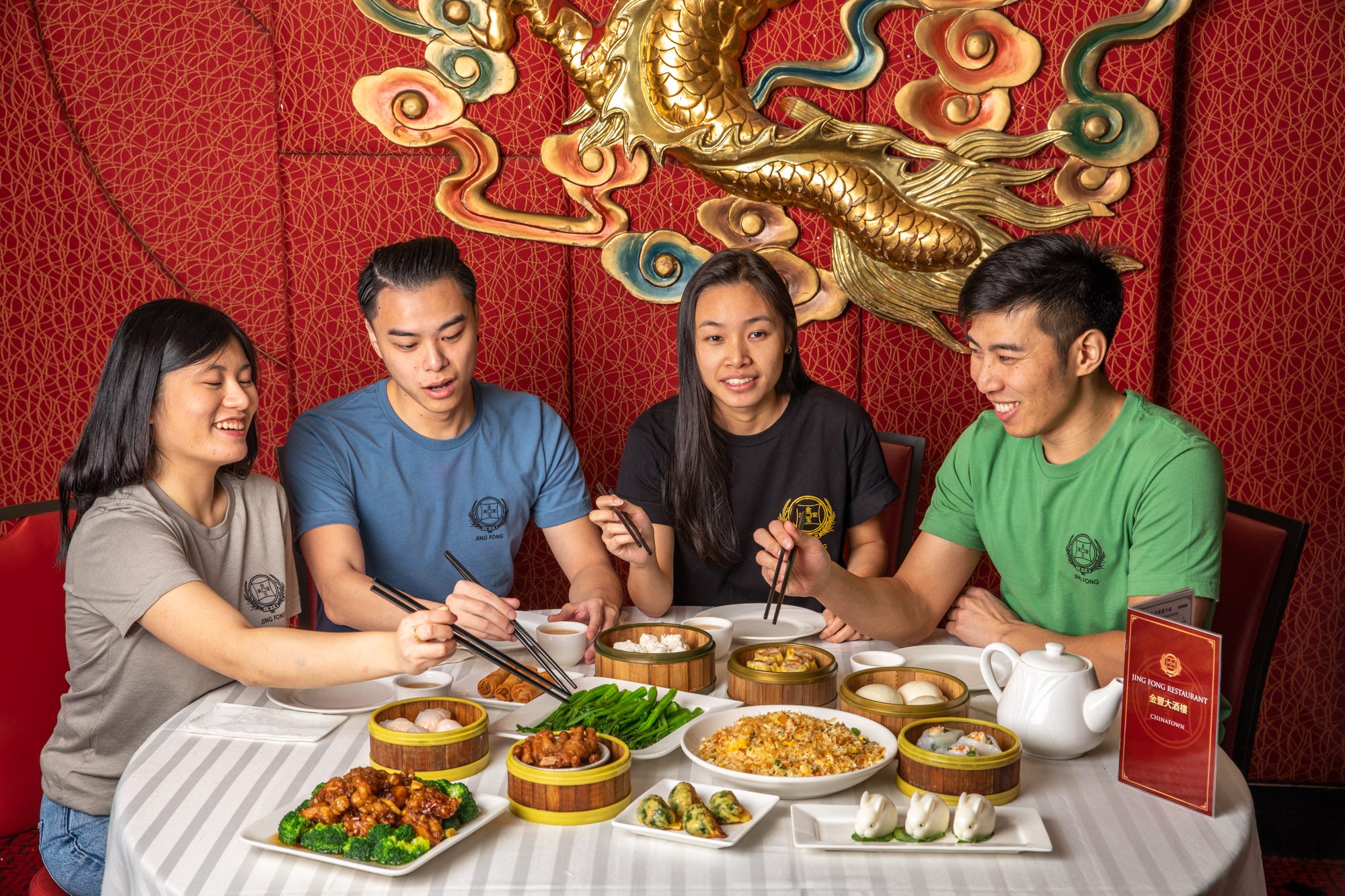 People sitting around a Dim Sum table reaching for food