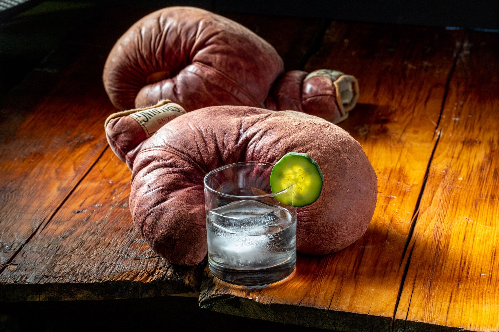Old timey boxing gloves with an old timey cucumber cocktail nestled in them