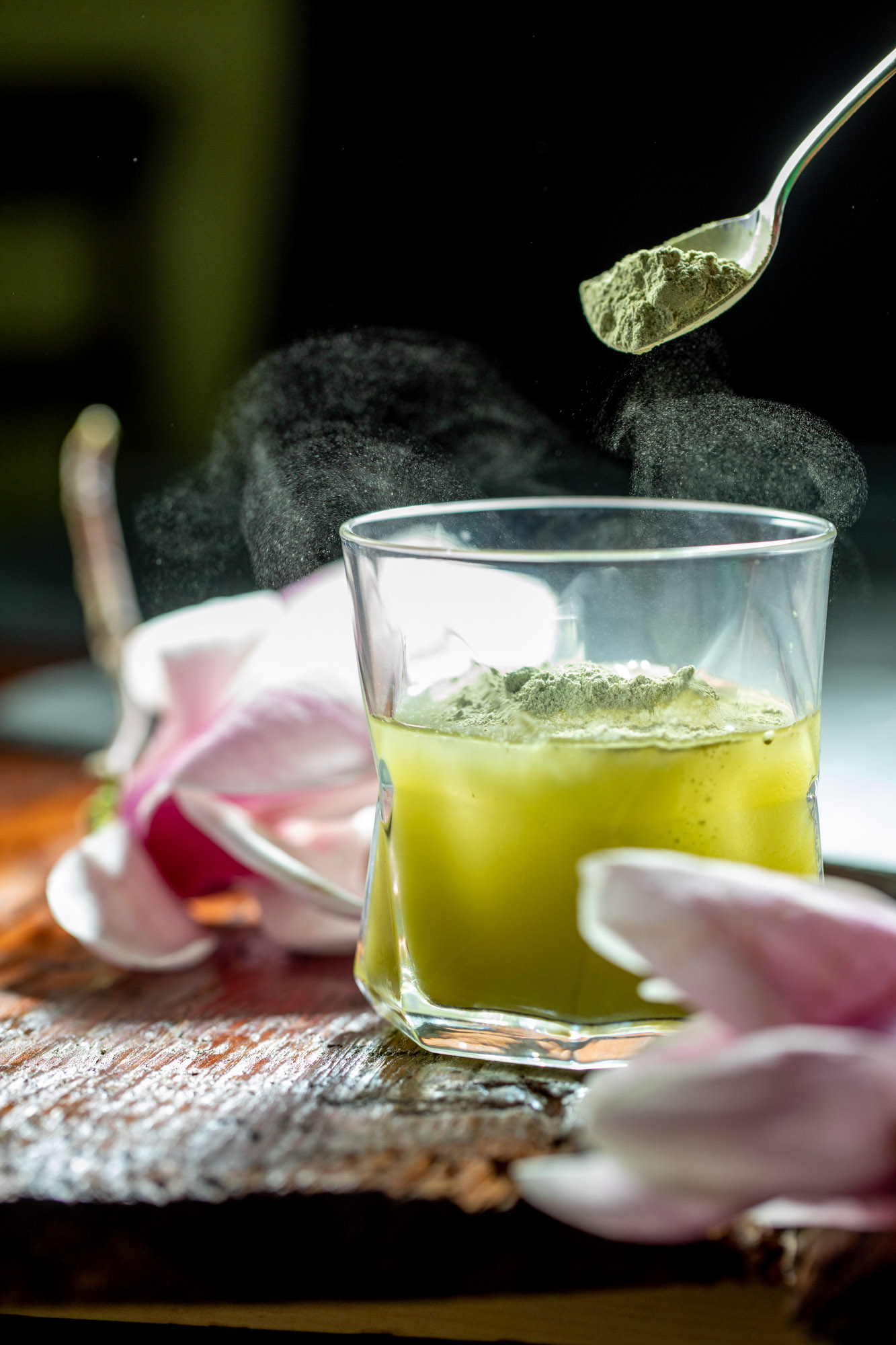 A spoon full of matcha being shaken into a drink