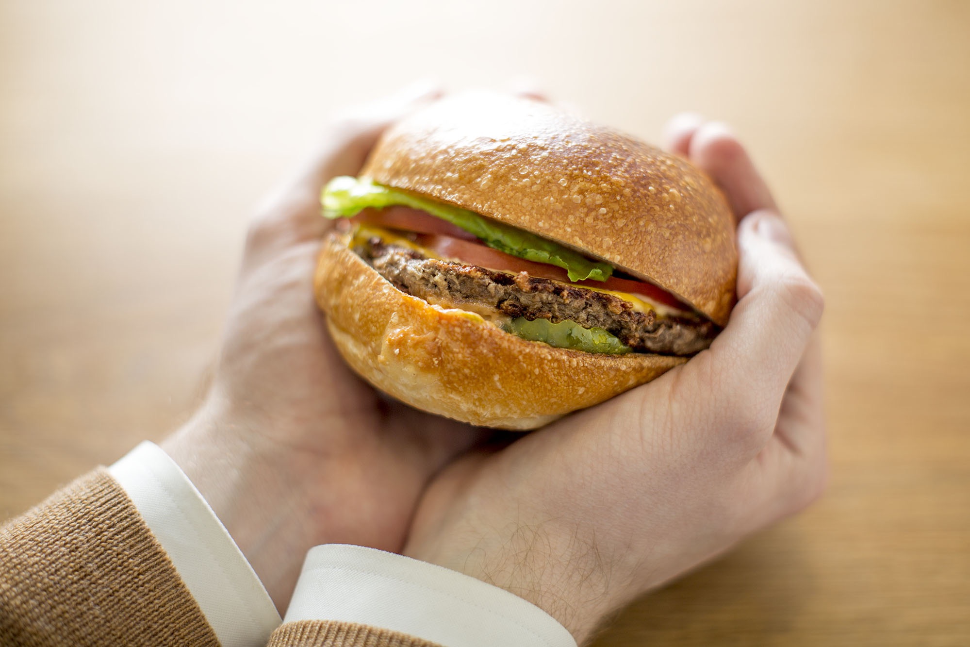 Hands holding an Impossible Burger.