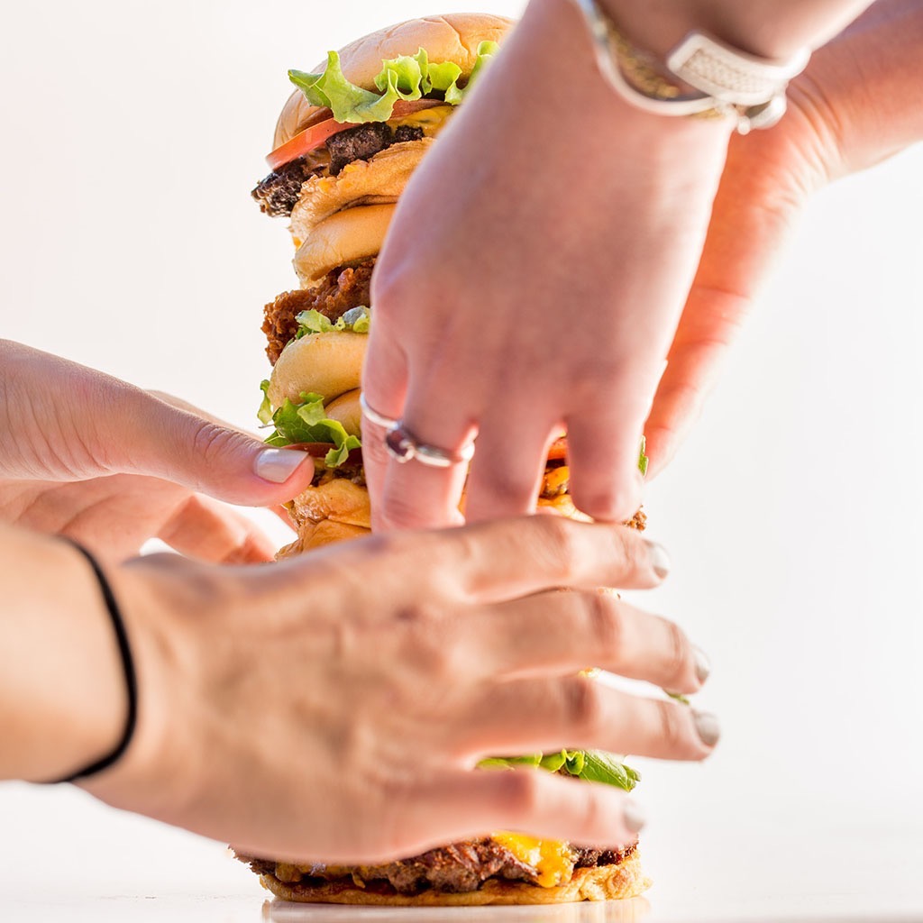 Hands food styling a stack of burgers