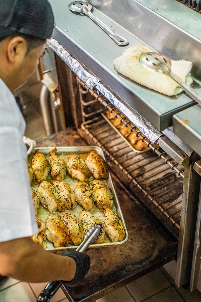 Chef putting a tray of chicken into the oven to cook