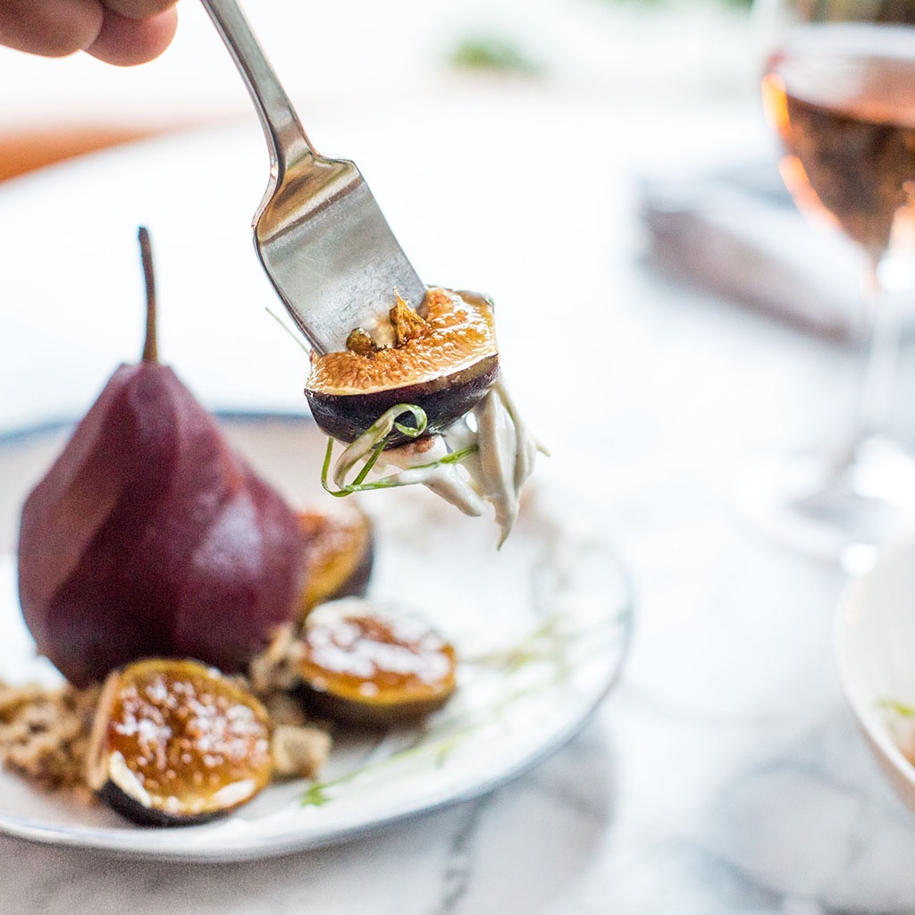 A fig resting on the end of a fork.