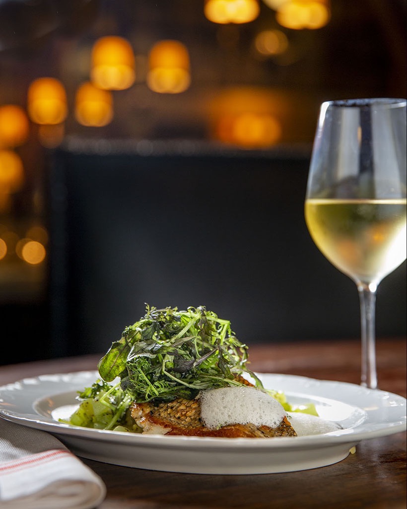 A branzino and a glass of wine photographed at a romantic restaurant