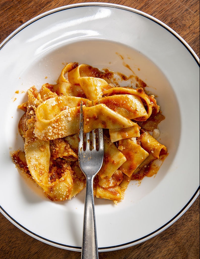 A fork sitting in a messy foodporn plate of food.