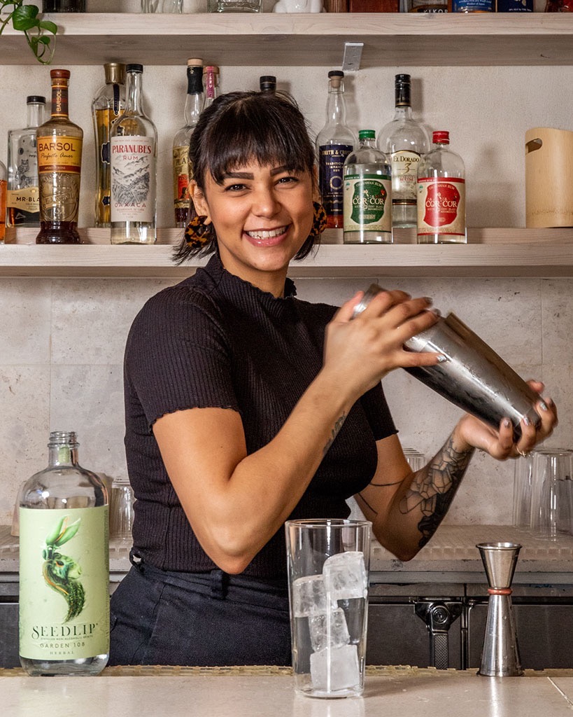 A bartender smiling and laughing while making a cocktail