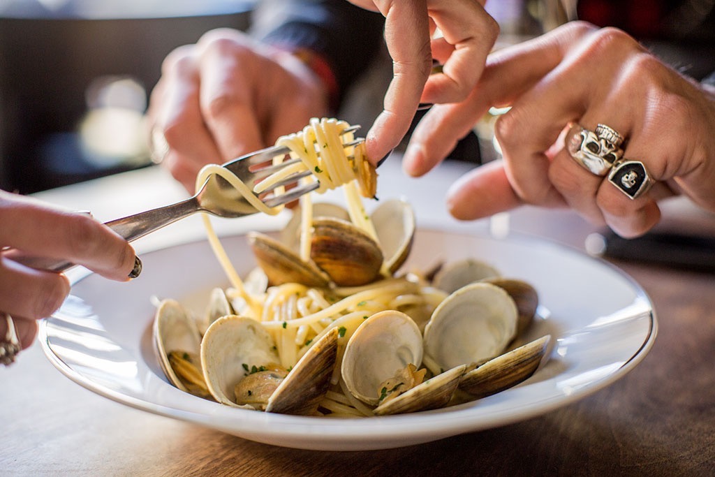 Many hands food styling a plate of spaghetti