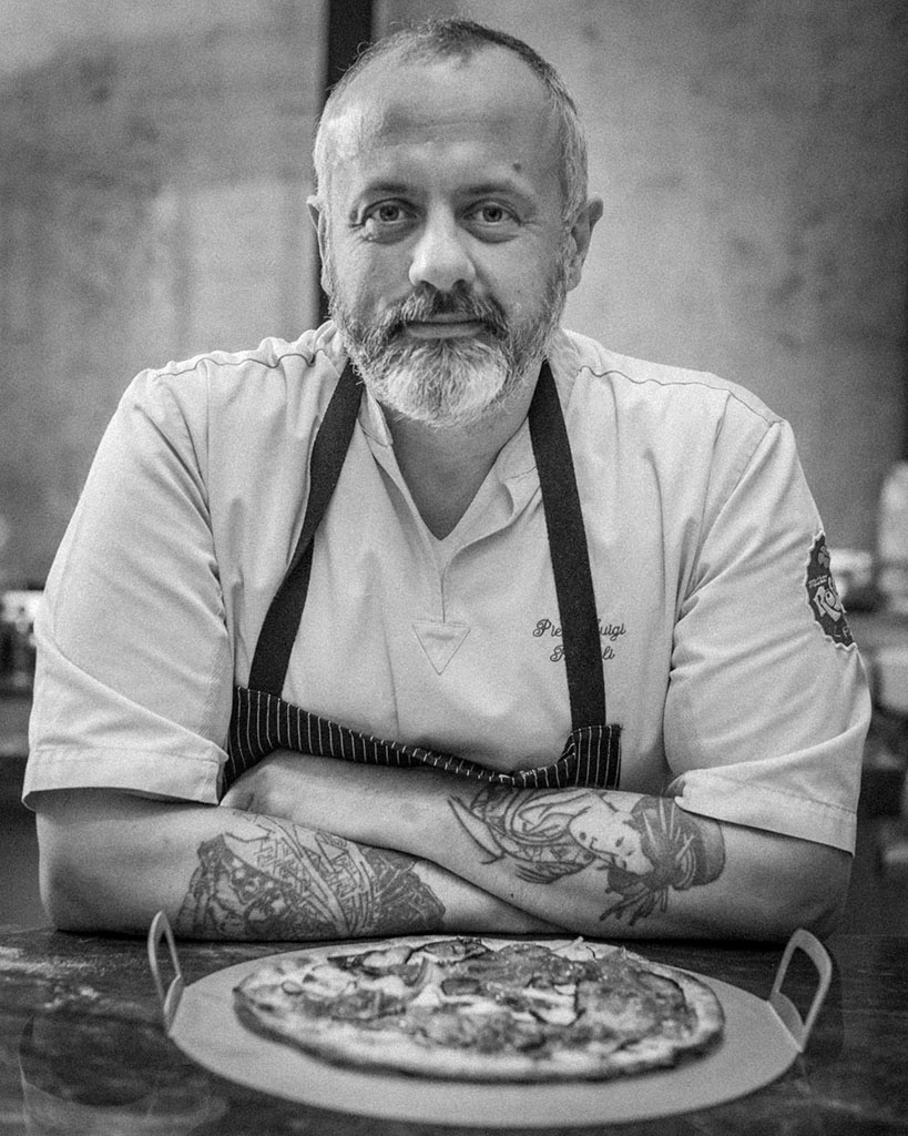 a master pizza chef posing in front of a pizza that he made