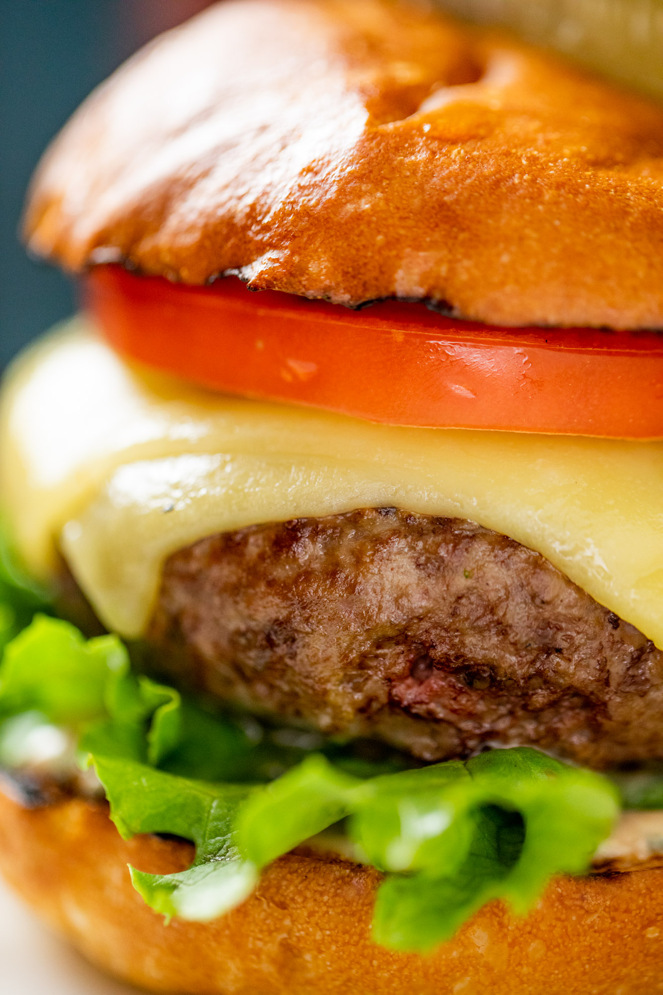 A burger with melty cheese and green lettuce.