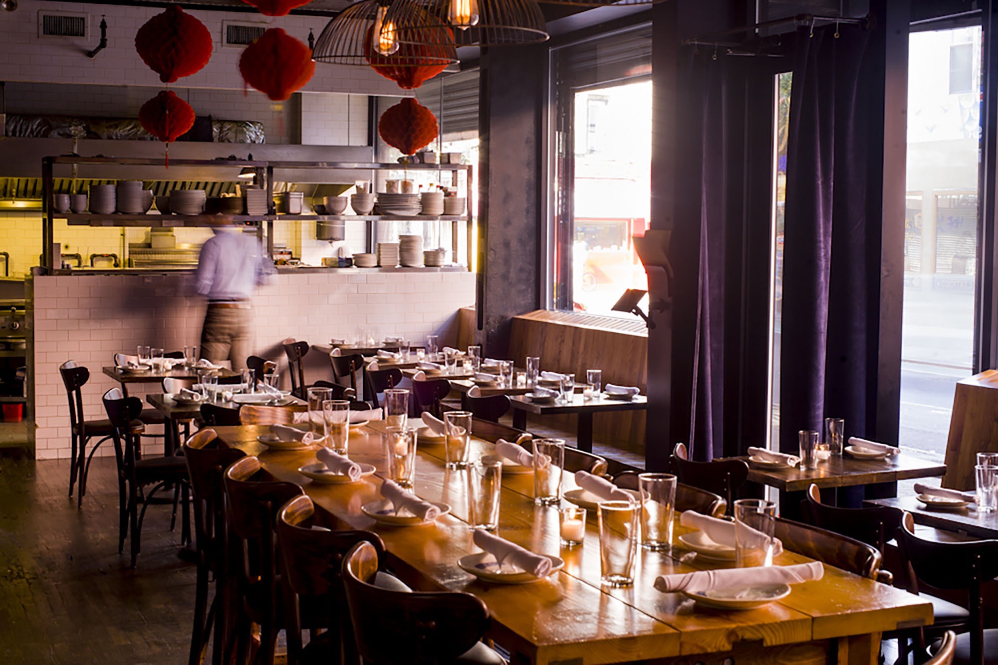 A waitor is setting the tables at an upscale chinese restaurant in the Lower East Side.